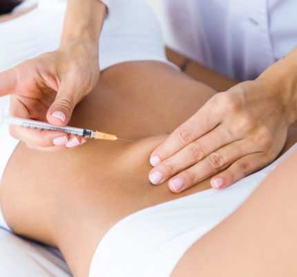 Portrait of surgeon making injection into female body. Liposuction concept.